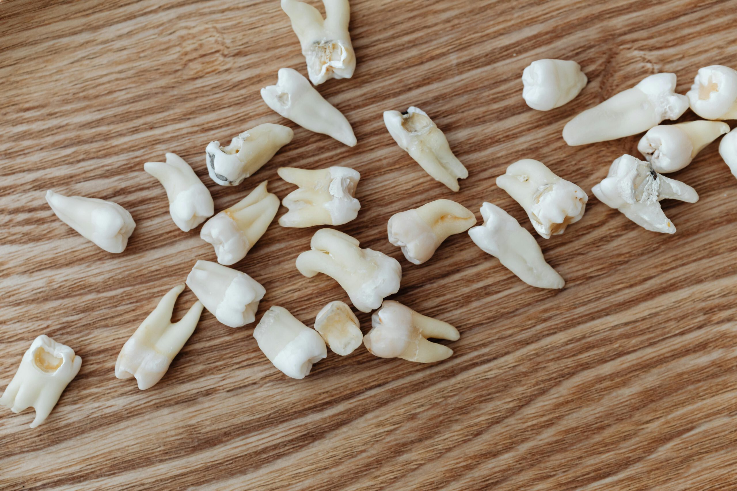 Close-up image of human teeth scattered on a wooden background, ideal for dental topics.